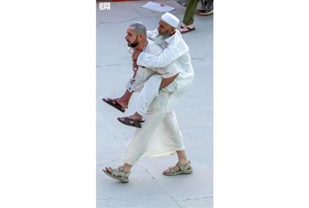 Pilgrim carries father on his back at Haj